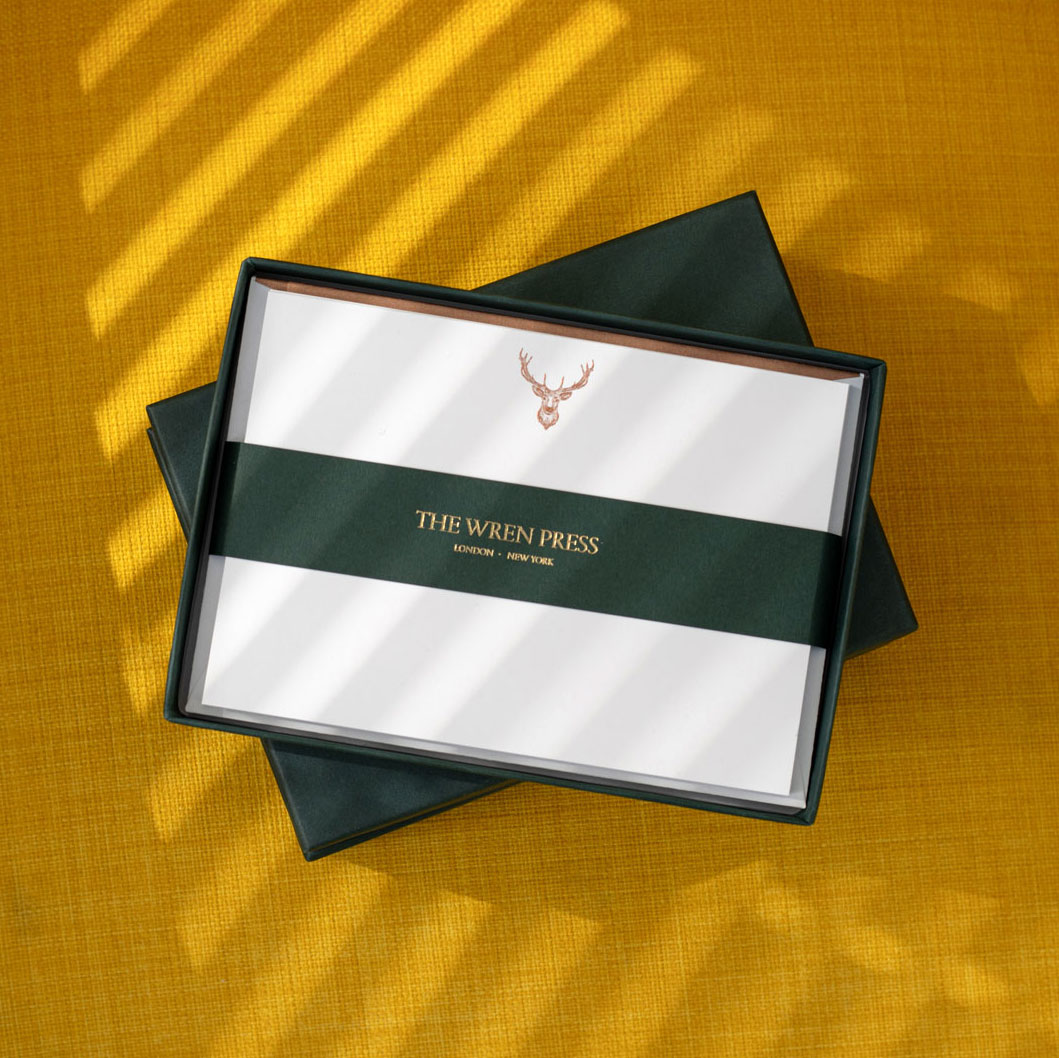 a box of correspondence cards with a stag logo engraved by hand at the top on a mustard yellow background