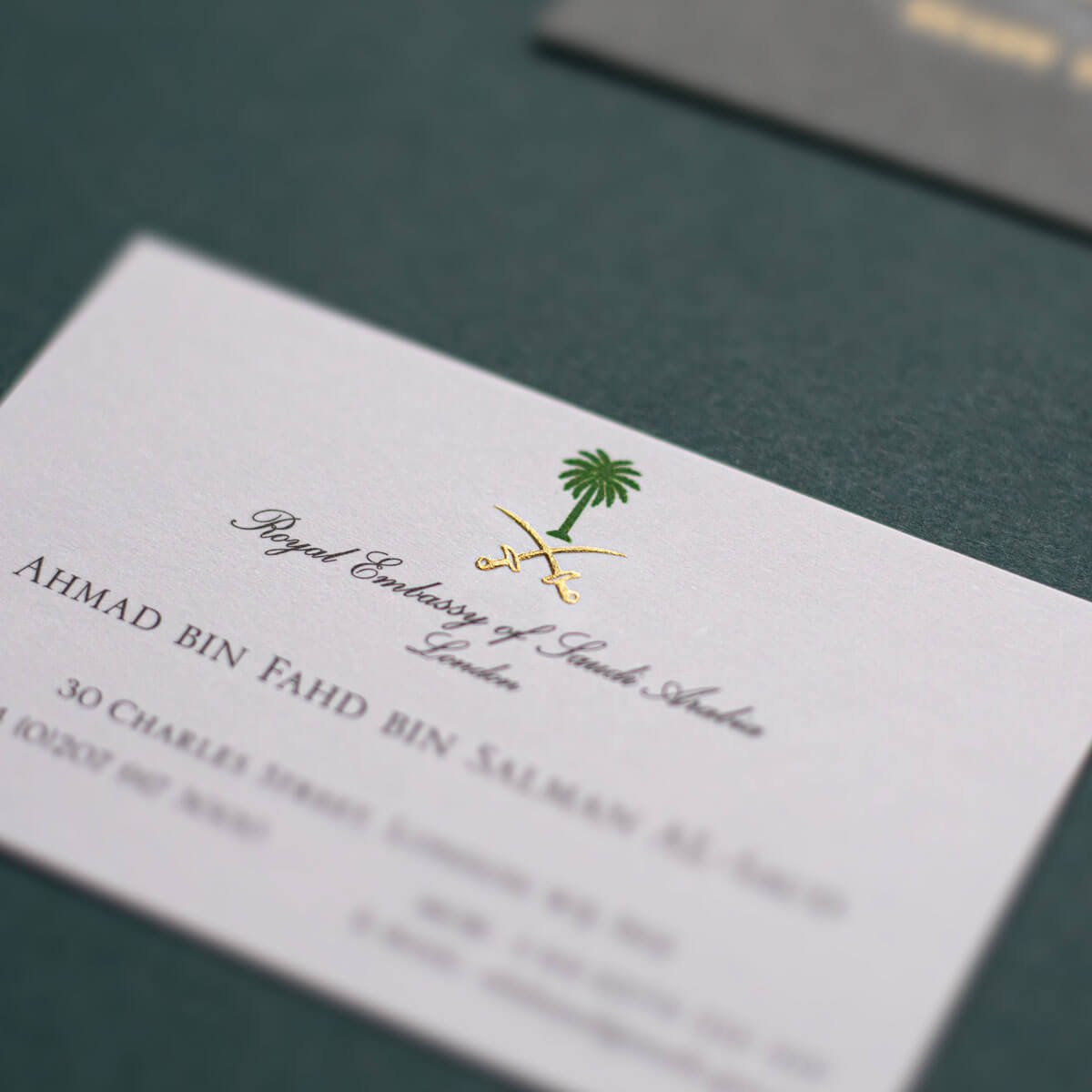 gold engraved logo of swords and green palm tree business card