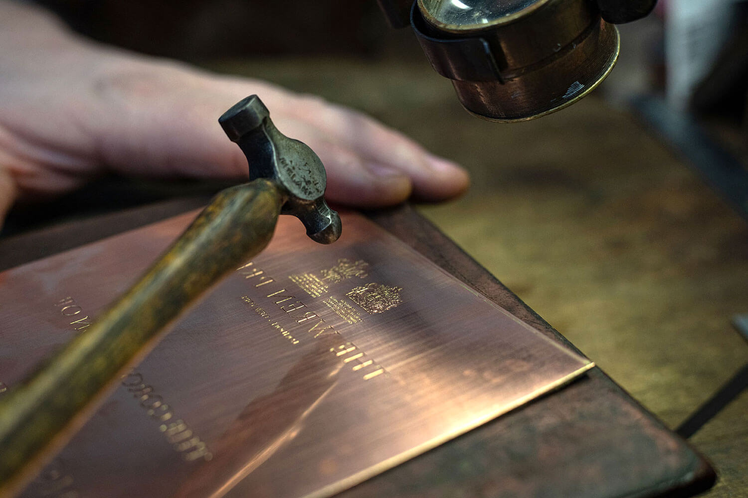 a copper plate being hand engraved by a hammer making crest designs for the wren press
