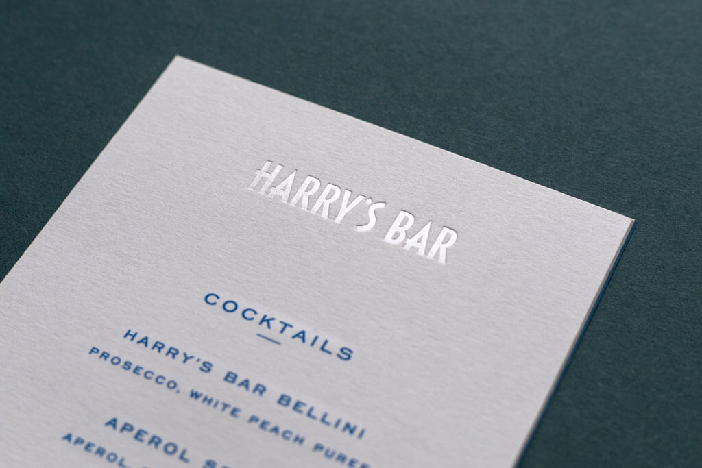 a cocktail menu with clear foiled logo on premium white board paper