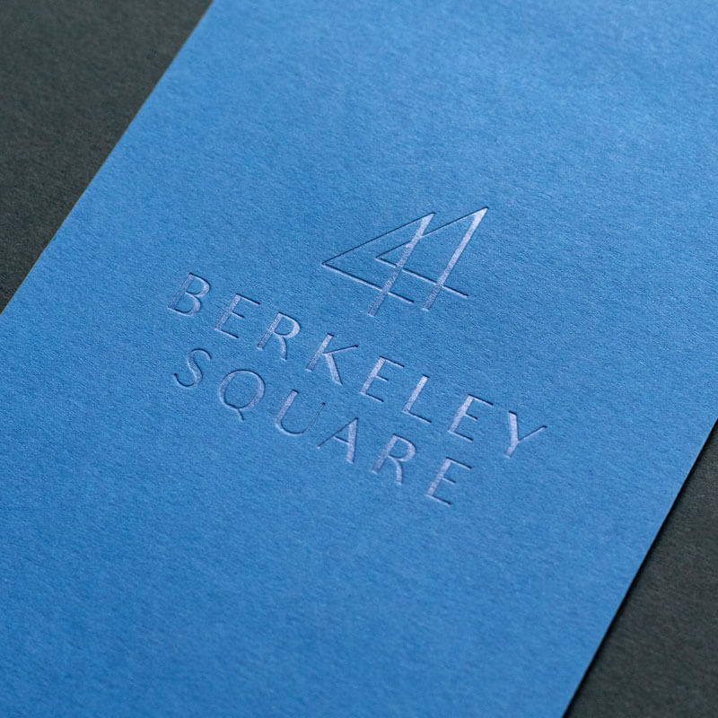 a premium blue paper board cocktail menu with a clear foiled luxury logo saying berkeley square
