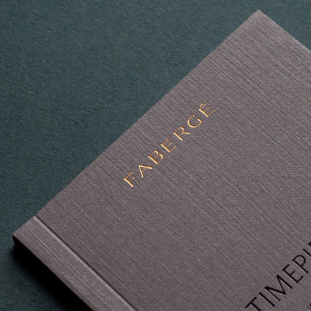a gold foiled faberge logo on a premium grey perfect bound brochure