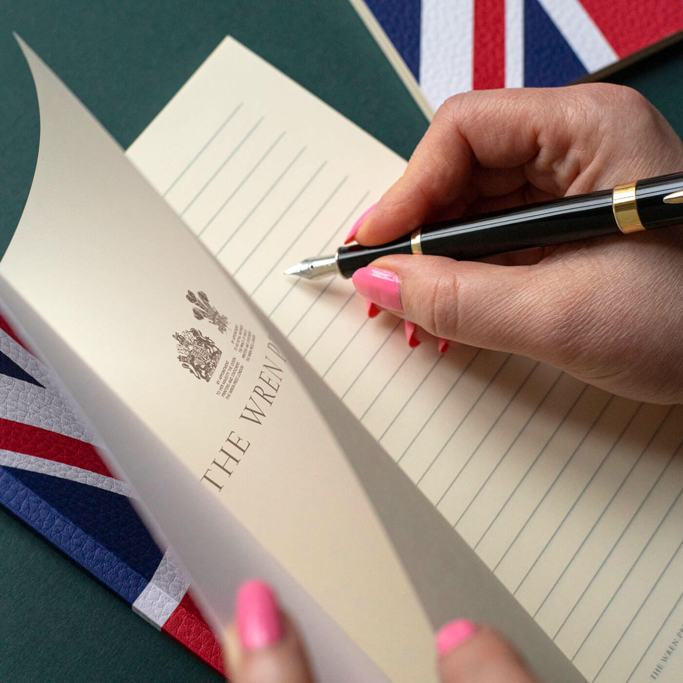 lady writing with pen on pages of textured union jack printed notebook