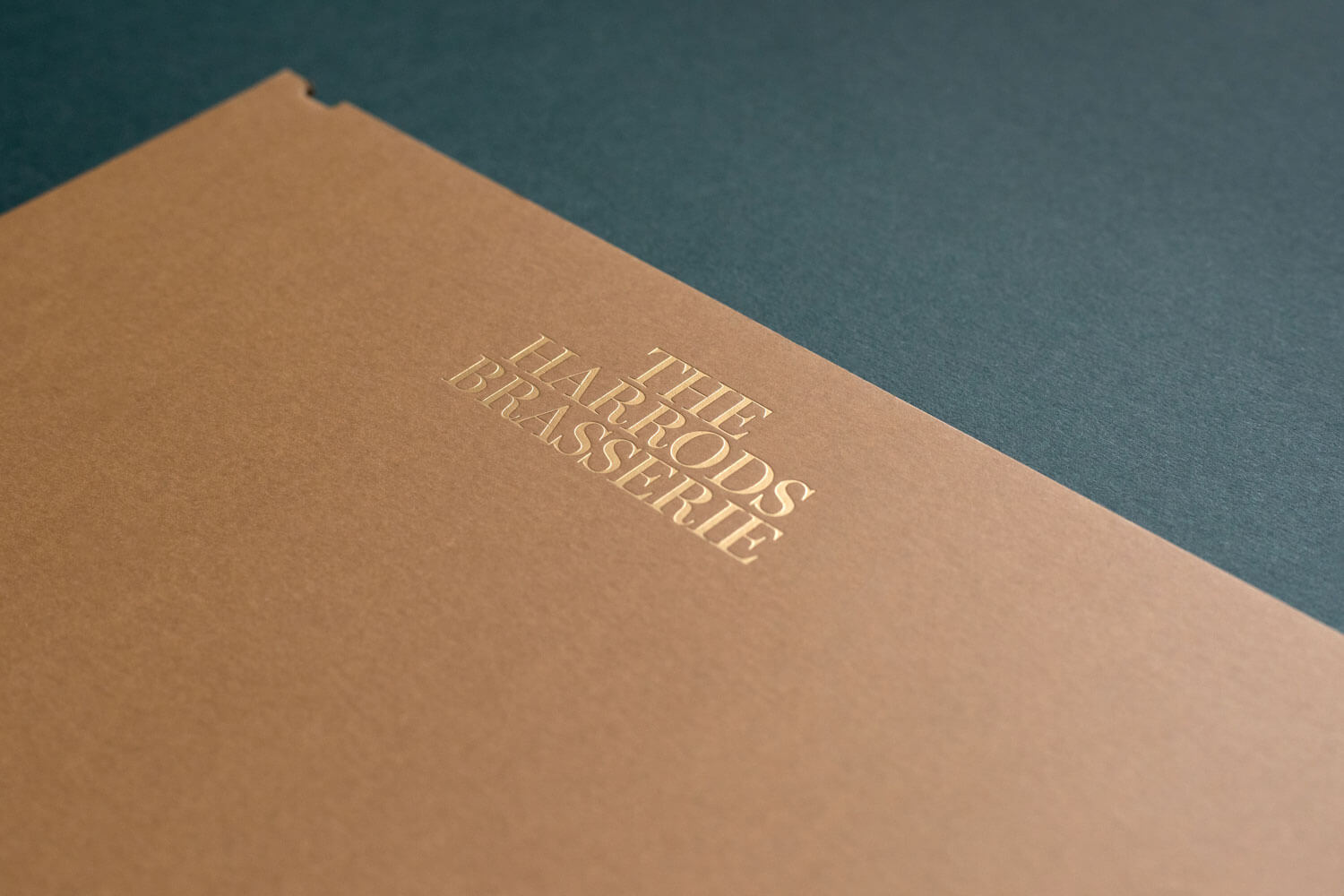 a tan coloured menu board with a luxurious gold foiled harrods brasserie logo