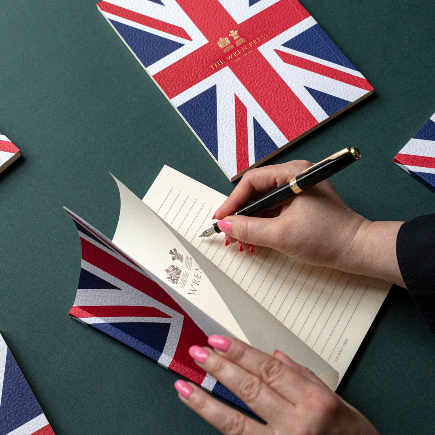 open pages union jack printed gold engraved notebook hands writing with pen